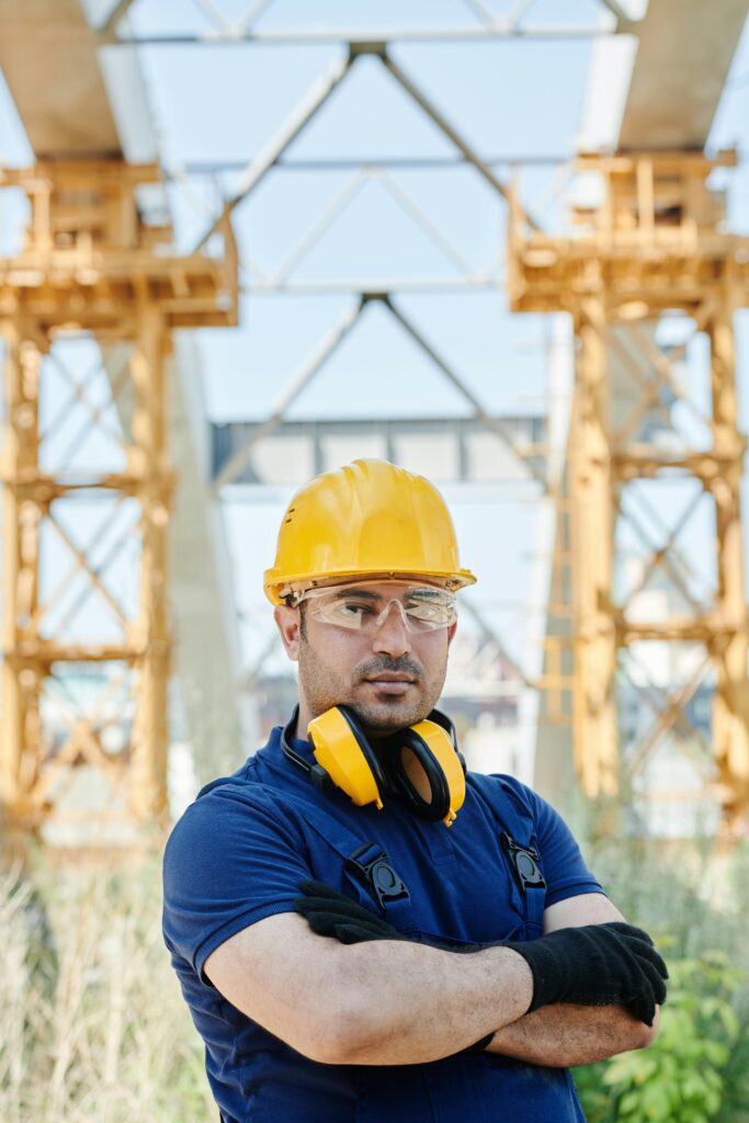 Confident engineer standing with protective gear at a construction site.